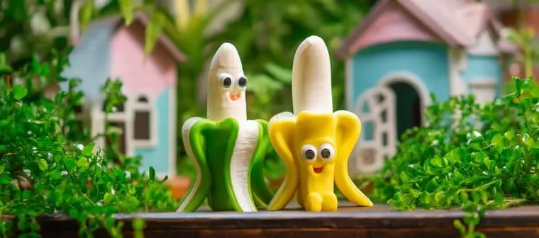 Brinquedos de vinil em formato de banana com rostinho, nas cores verde e amarela